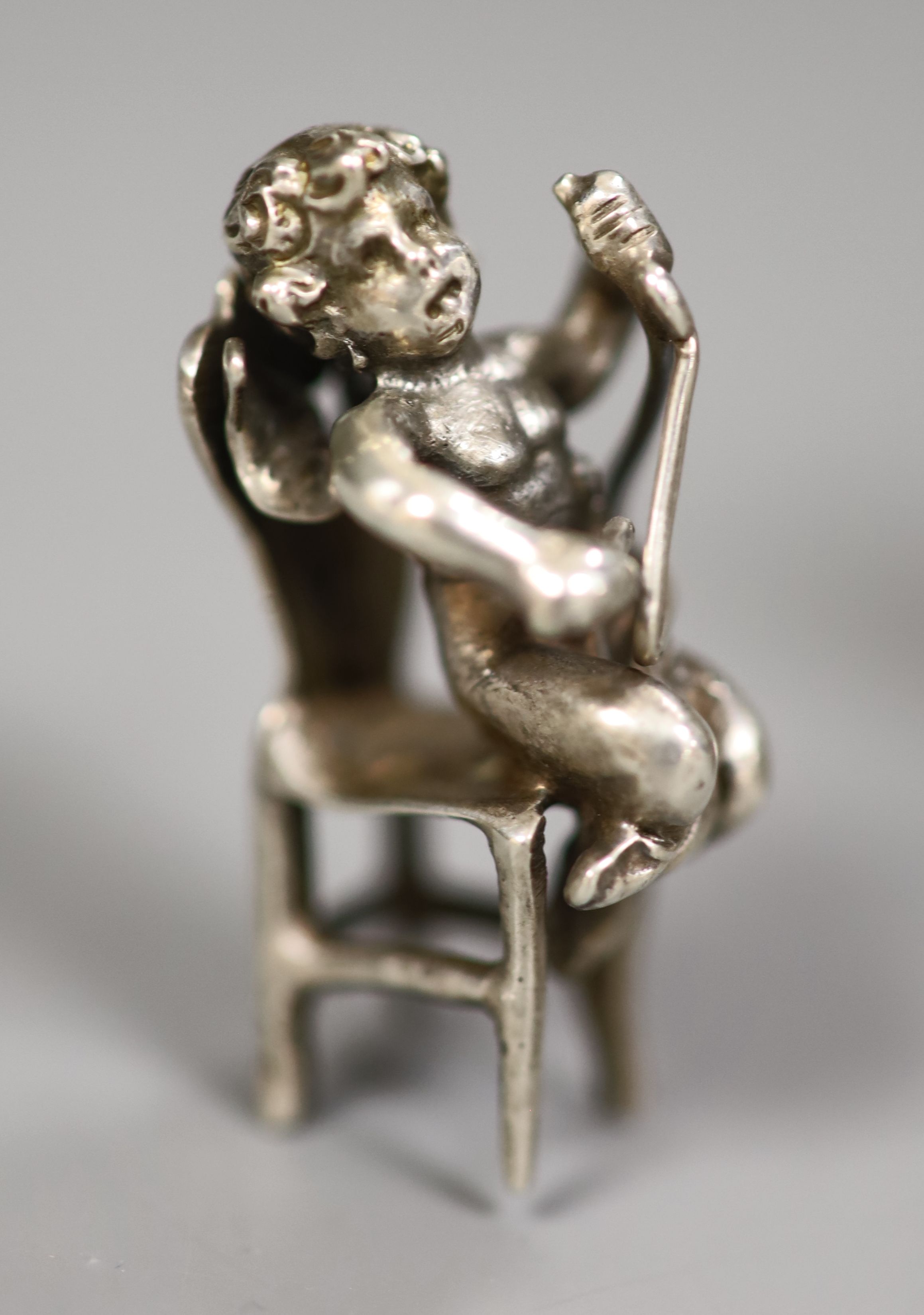 An early 20th century Continental white metal toy chariot, 10.3cm, a silver cherub on a chair and a silver Cupid desk seal
